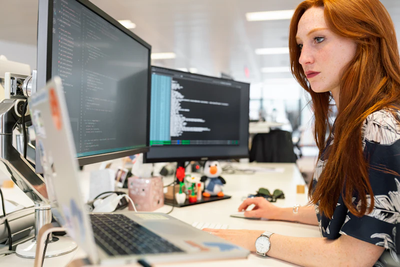 Developer concentrating on code across two screens