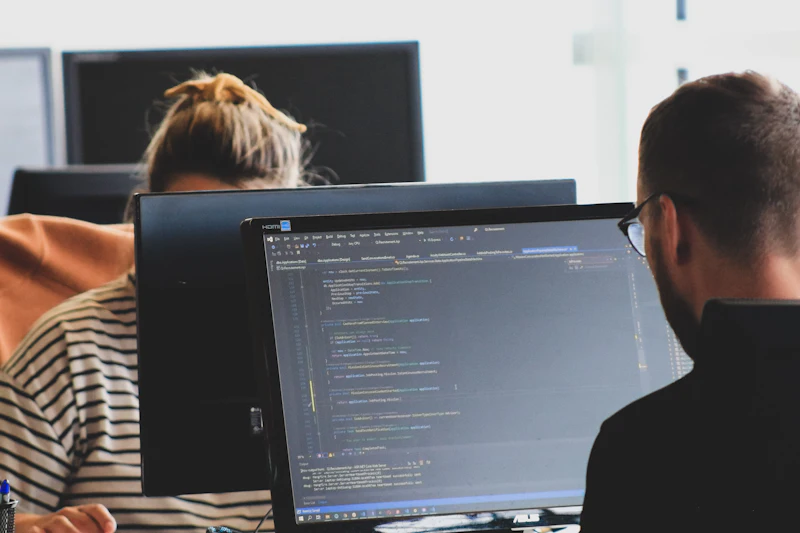Two developers working on code on large screens