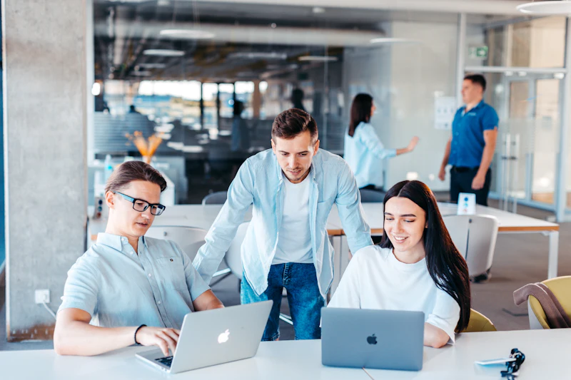 Three colleagues working together on laptops in a bright office